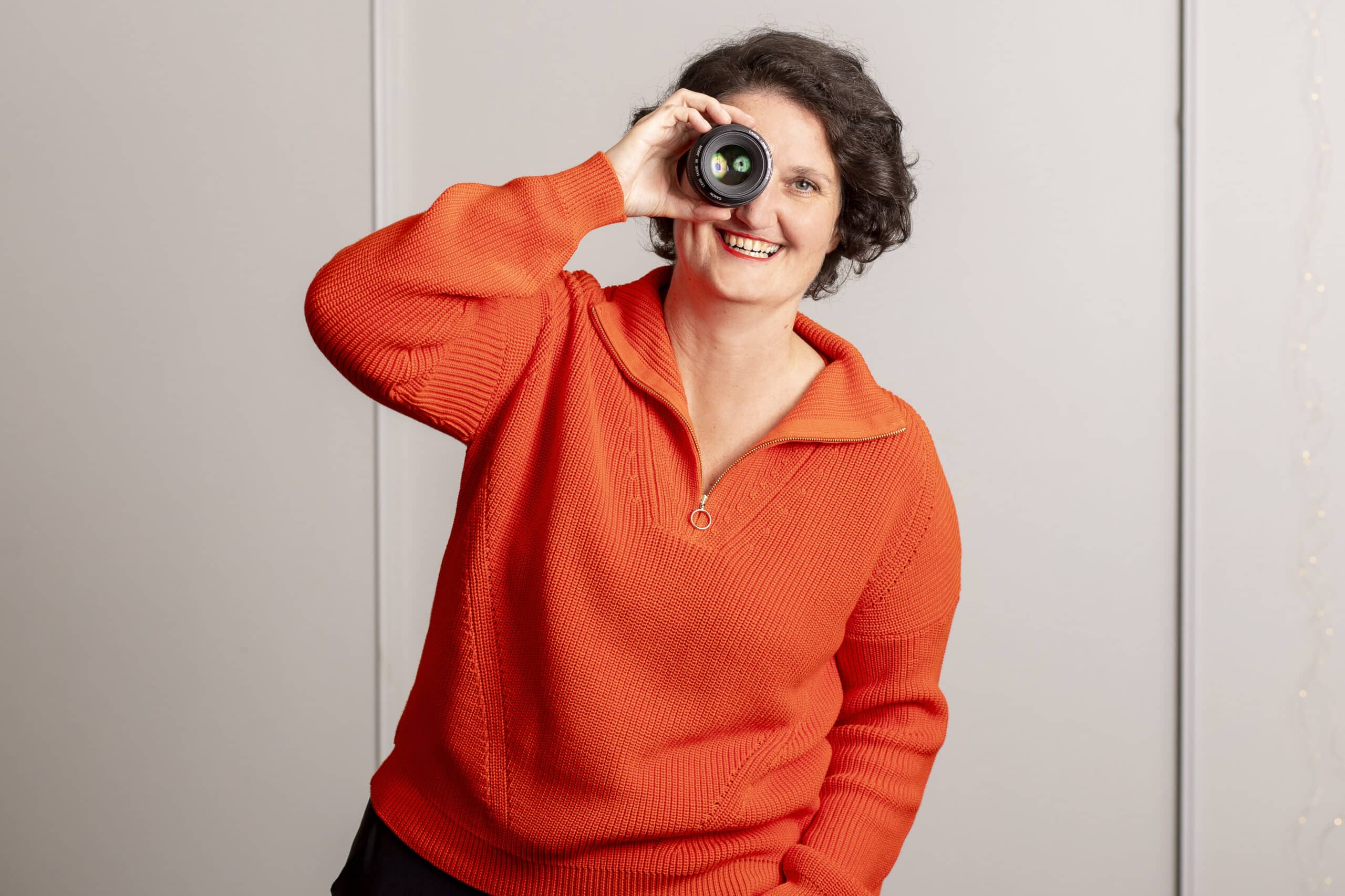 Portrait_AnnSophieDetje_FotografinPersonalBranding Foto von einer Frau mit Fotoobjektiv in der Hand.