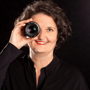 Es ist ein Foto von eine Frau mit einer Fotolinse vor dem rechten Auge zu sehen. Ann Sophie Detje Fotografin für Markenpersönlichkeiten im Business.